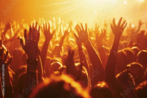 A side view of a lively crowd at a concert, with everyone enthusiastically raising their hands in the air