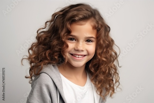 Portrait of a happy smiling little girl with curly hair over gray background