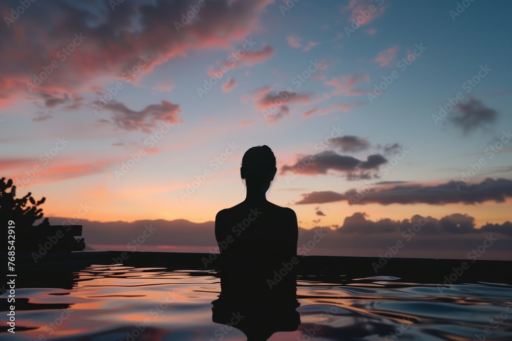 silhouette of a person enjoying an onsen with sunset colors in the sky