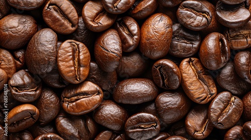 Close-up of roasted coffee beans. Dark brown and oily, the beans are arranged in a haphazard pattern. photo