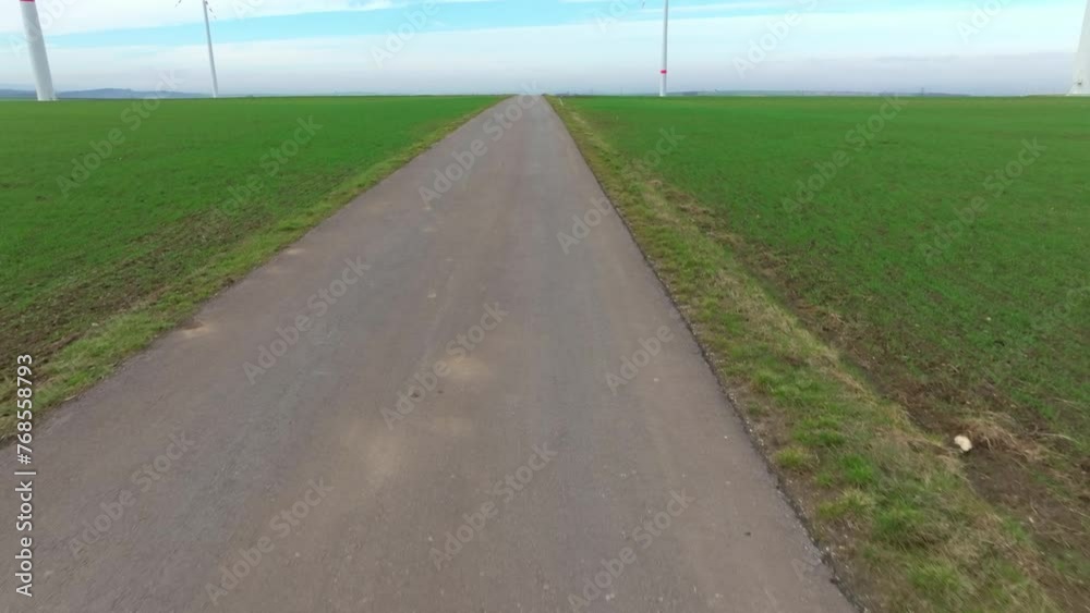 Road Along The Green Field With Wind Turbines. - aerial tilt up shot Road Along The Green Field With Wind Turbines. - aerial tilt up shot
