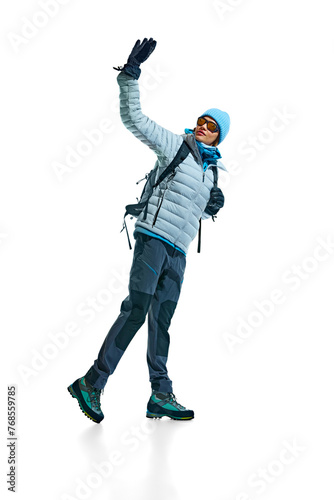 Young woman, climber wearing jacket, hat, goggles, backpack and durable footwear for hiking activity isolated on white background. Active lifestyle, tourism, mountaineering, sport, travelling concept