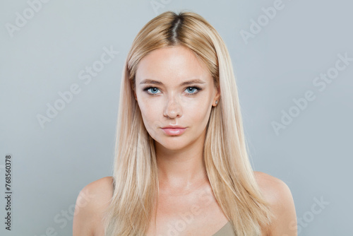 Stylish young blonde lady with fresh clear skin and long smooth straight hairstile on white background