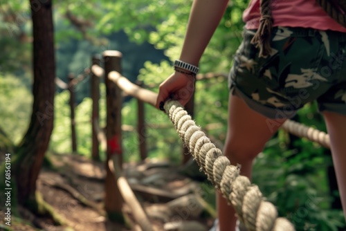 young adult using a rope handrail on a nature trail © studioworkstock