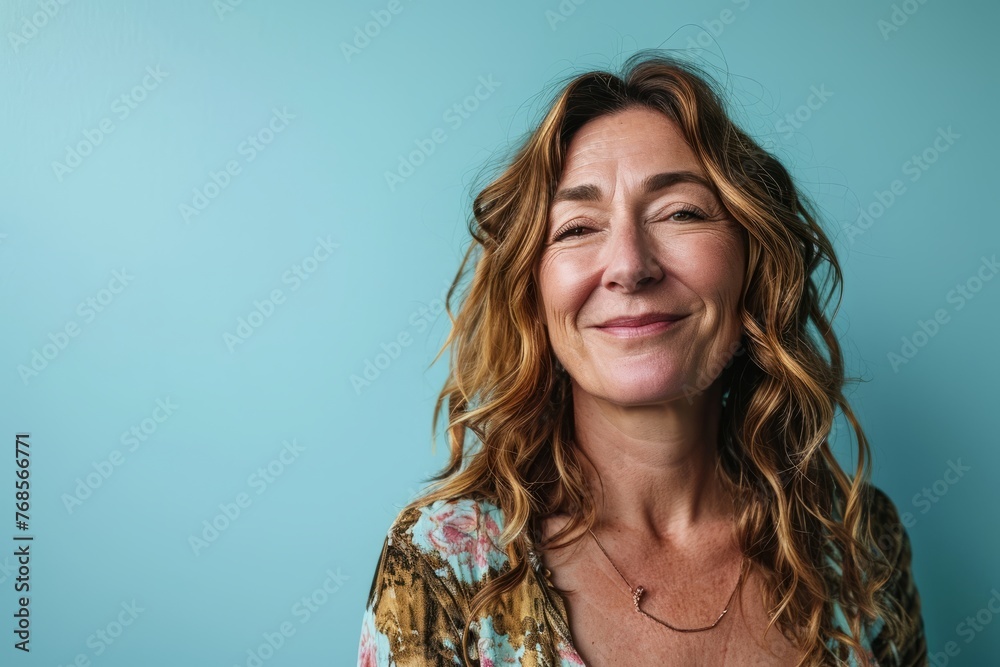 Portrait of smiling middle aged woman with long wavy hair against blue background Portrait of smiling middle aged woman with long wavy hair against blue background