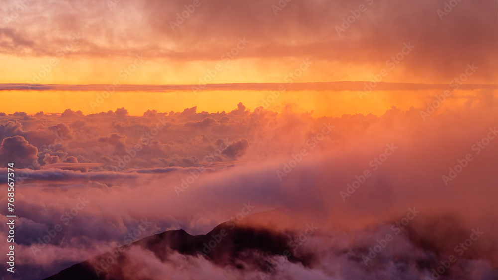 View of the stunning sunrise through the clouds over Haleakala volcano summit at Haleakala National Park on the island of Maui, Hawaii, USA