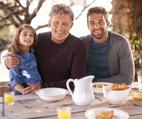 Outdoor, portrait and father with grandpa of girl, smile and breakfast on table in backyard of house. Home, men and child with happiness for visit to grandparent for holiday, family and love