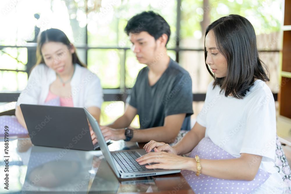 Three male and female Asian students working during summer break. It is in the cafe and there is a library for reading and acquiring knowledge in studying and submitting work to teachers. Three male and female Asian students working during summer break. It is in the cafe and there is a library for reading and acquiring knowledge in studying and submitting work to teachers.