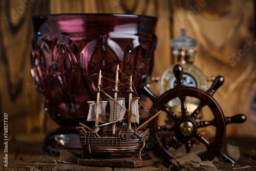 toy ship in a burgundy glass, with a ship wheel and compass as props