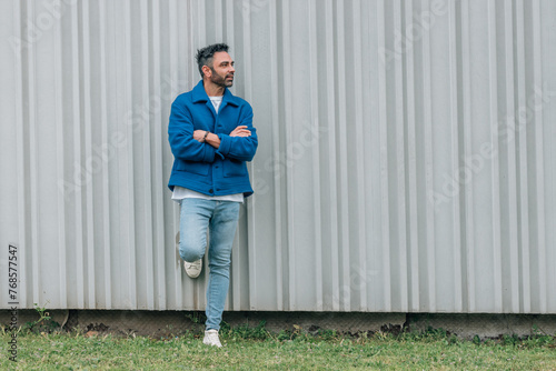 young man in blue jacket outdoors at wall with copy-space