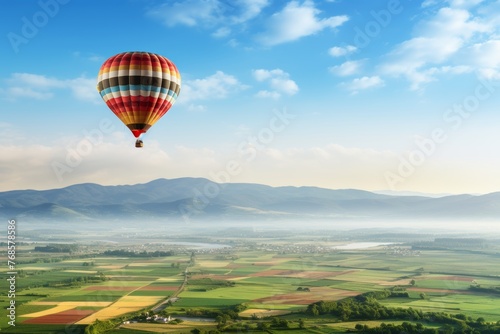 Aerial view of hot air balloon flying above verdant fields with ample copy space