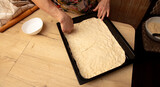 A woman makes a pie from dough on a baking sheet
