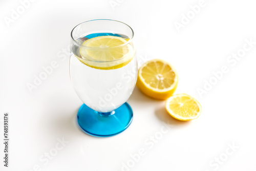 Lemon water in a glass and half a lemon on a white background. Photo