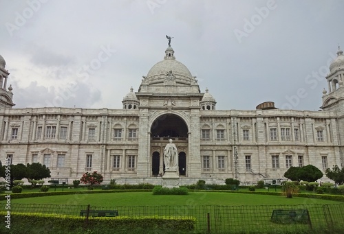 The grand Victoria Memorial Hall stands under a dramatic cloud-filled sky, showing off its exquisite colonial architecture with its towering domes and intricate stonework.