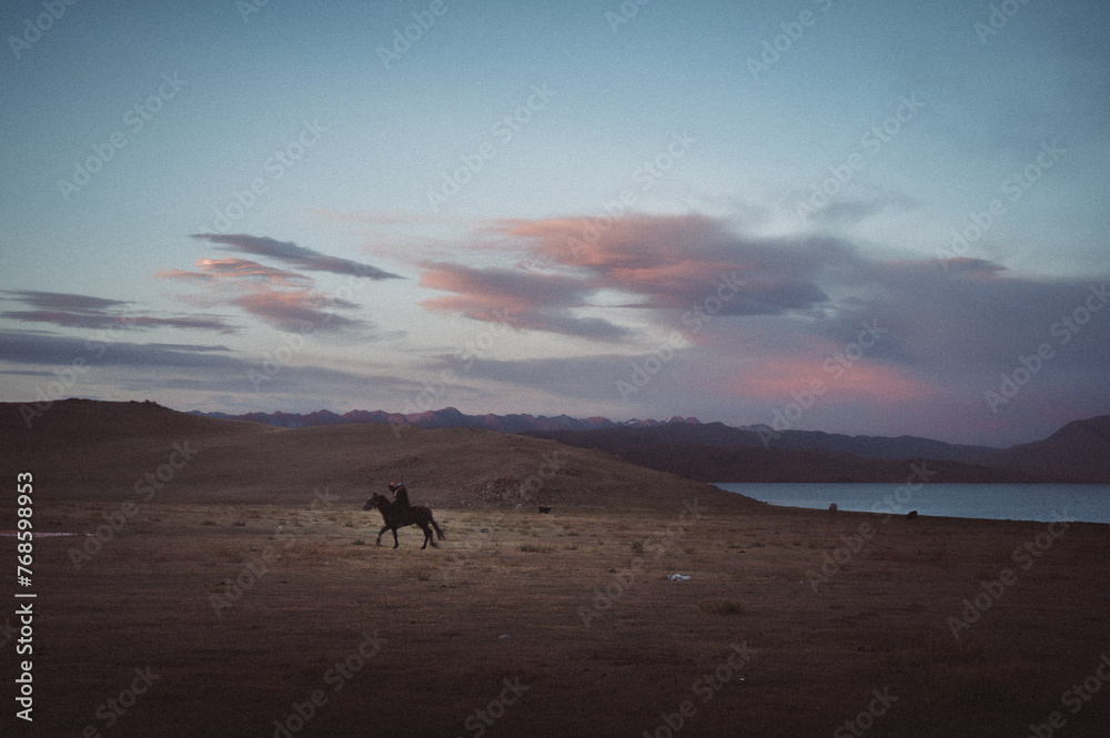 Scenic landscape in Kyrgyzstan featuring traditional yurts nestled amidst majestic mountains, with horses grazing peacefully. Authentic nomadic lifestyle captured in stunning imagery. Ideal for stock 