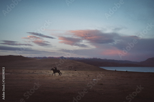 Scenic landscape in Kyrgyzstan featuring traditional yurts nestled amidst majestic mountains  with horses grazing peacefully. Authentic nomadic lifestyle captured in stunning imagery. Ideal for stock 
