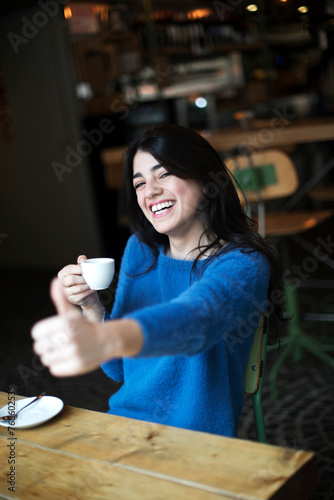 Woman laughing with coffee at cafe