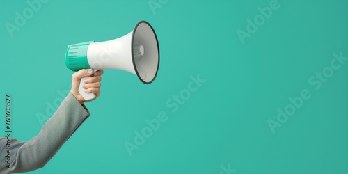 With a copy space for text, the hand holding the megaphone is accompanied by a grey suit on a background of green, mint, or Tiffany blue. photo
