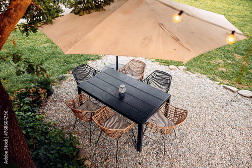 Fotografía modern cozy backyard garden features a wooden table, chairs, and umbrella set am