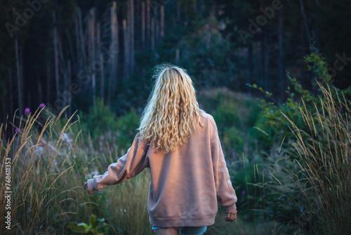Young Blonde Girl Walking in Dark Forest