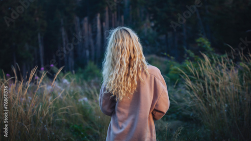 Young Blonde Girl Walking in Dark Forest