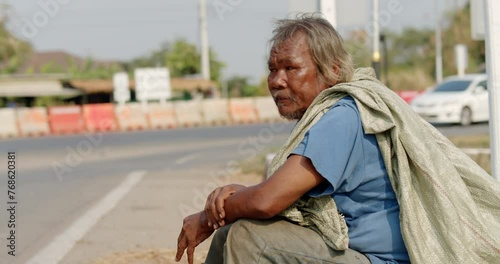 An Asian man who is a poor ragpicker or collects garbage and sells, sitting on the side of the road in the morning photo