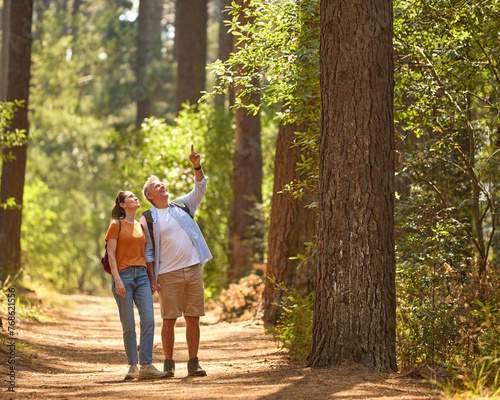 Senior Man Pointing As Retired Couple Hold Hands And Hike Along Trail In Countryside