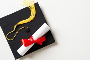 Graduation cap and diploma isolated on white background. Flat lay, top view.