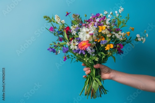 Hand holding a cheerful mix of colorful fresh flowers