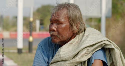 An Asian man who is a poor ragpicker or collects garbage and sells, sitting on the side of the road in the morning photo