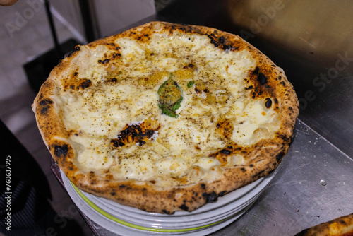 Pizza tradizionale napoletana con provola, pepe, basilico e tarallo sbriciolato appena sfornata e pronta per essere servita in una pizzeria