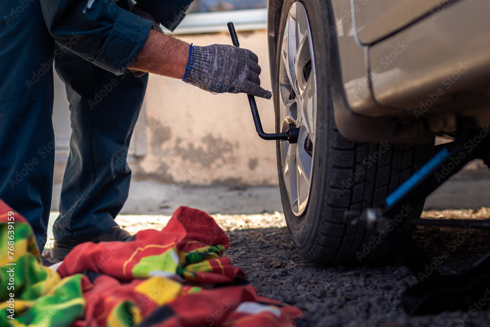 Obraz premium Man changing his own car tire for summer season.