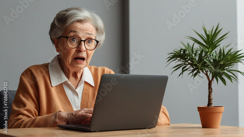 Surprised senior woman in eyeglasses using laptop at home