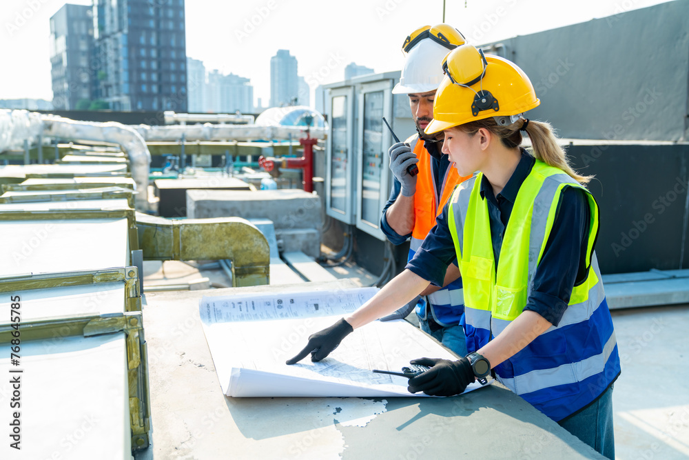 Professional Asian man and woman teamwork engineer and foreman using blueprint working outdoor at construction site building rooftop. Architecture inspector inspect building exterior structure system.