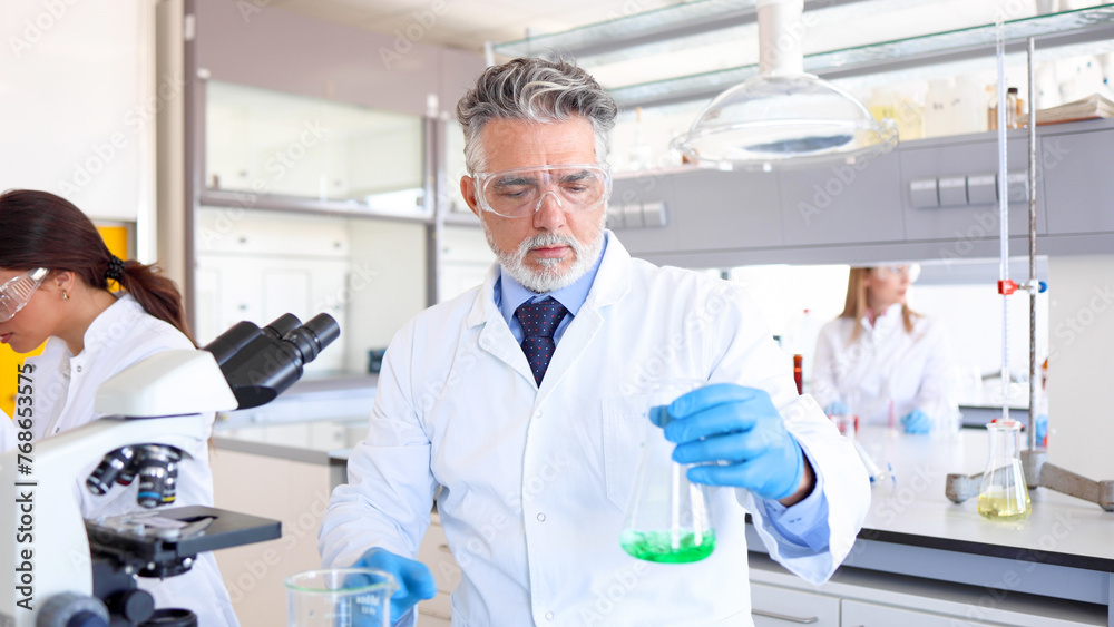 Mature scientist and his team working at the laboratory Mature scientist and his team working at the laboratory