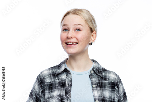 The young girl laughs. A cute blonde with freckles on her face wearing a black and white checkered shirt and a blue top. Positivity, optimism and charm. Isolated on a white background. Close-up.