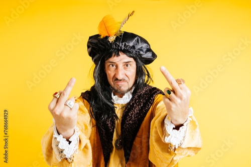 Noble Aristocrat in Period Costume Gesturing Disrespectfully Against a Yellow Background photo