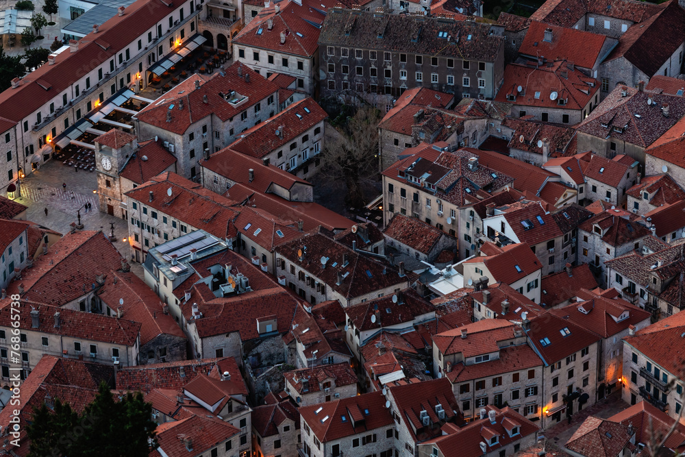 Aerial view of Kotor Old Town at twilight, warm lights contrast against the cool dusk shades over stone buildings. Montenegro