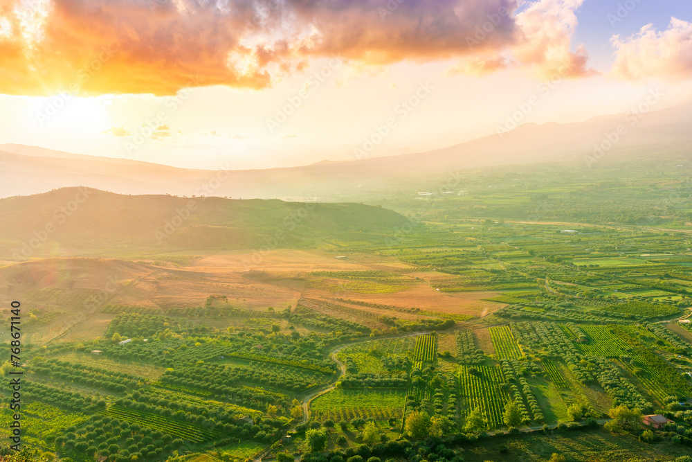 scenic rustic landscape with green hills and farms in a mountain valley during colorful cloudy sunset scenic rustic landscape with green hills and farms in a mountain valley during colorful cloudy sunset