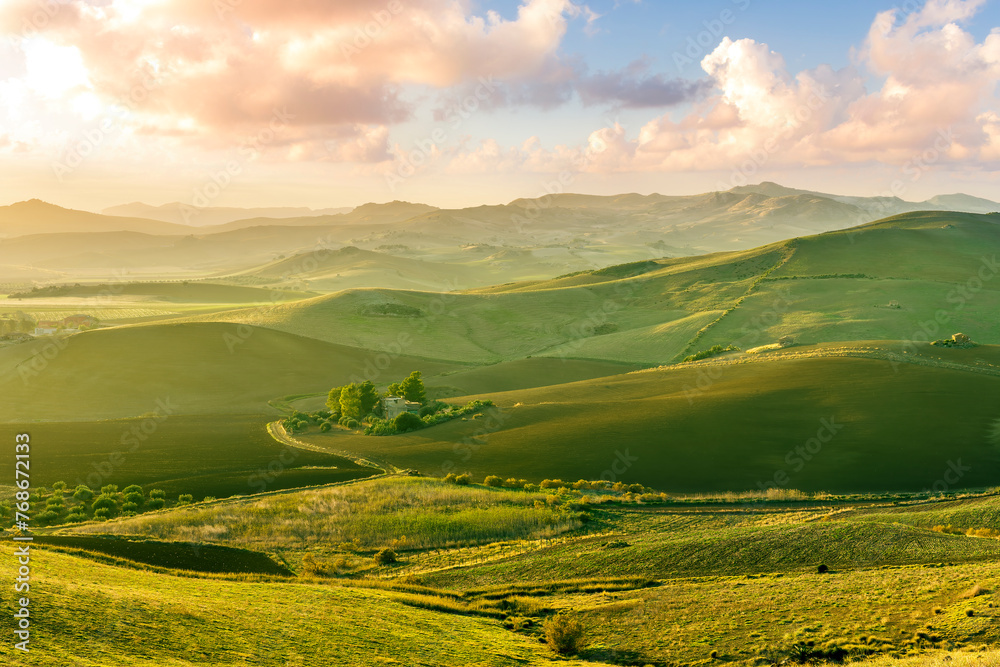 Fototapeta premium spring green field landscape in beautiful countryside with green and yellow grass, rural hills and amazing cloudy sky on background. Agriculture landscape with rural view
