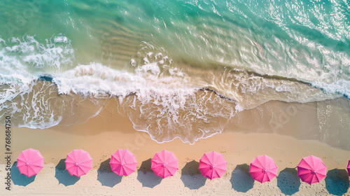 Beach with pink umbrellas, top view, drone photo, sea waves in the background, summer vacation concept