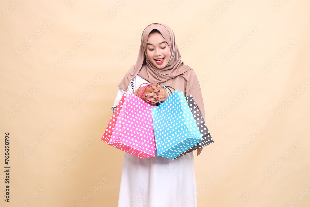 the charm of a young Asian Muslim woman wearing a hijab looking at the contents of her shopping and carrying the contents of a top-down paper bag. for advertising, lifestyle, banners and Ramadan the charm of a young Asian Muslim woman wearing a hijab looking at the contents of her shopping and carrying the contents of a top-down paper bag. for advertising, lifestyle, banners and Ramadan