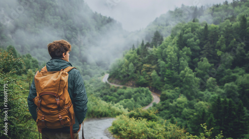 
A traveler standing at the edge of a lush forest, backpack slung over their shoulder, gazing out at a winding path disappearing into the trees photo