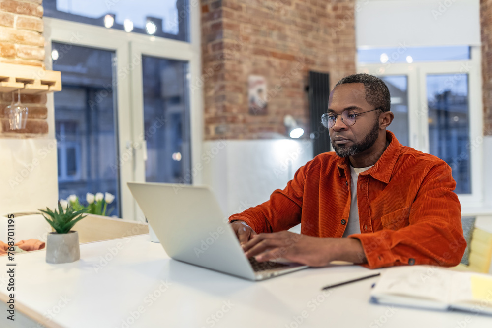 Dark-skinned man in red shirt working and looking involved Dark-skinned man in red shirt working and looking involved