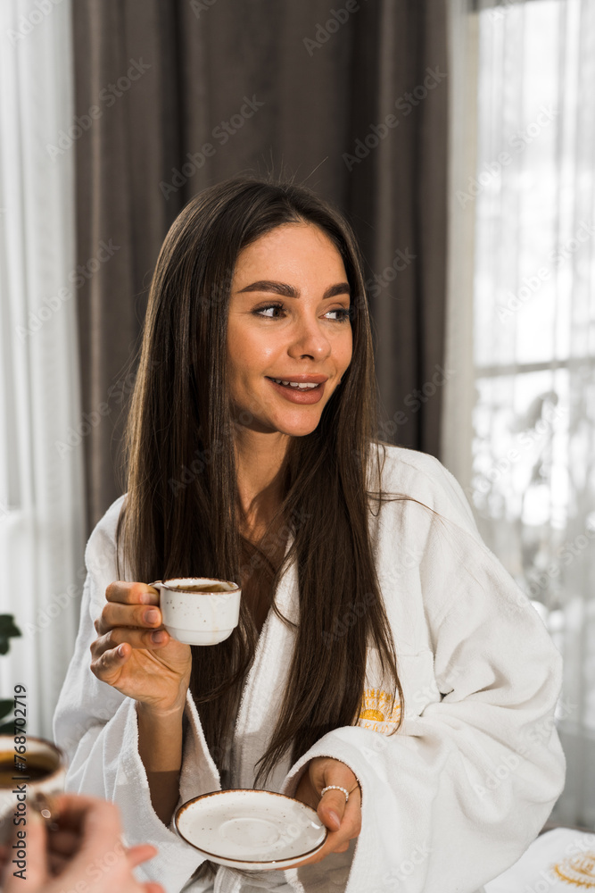 Young women in bathrobes have breakfast in bed, drink coffee and fool around. Breakfast cheesecakes and fruits with coffee. Hotel holiday concept Young women in bathrobes have breakfast in bed, drink coffee and fool around. Breakfast cheesecakes and fruits with coffee. Hotel holiday concept