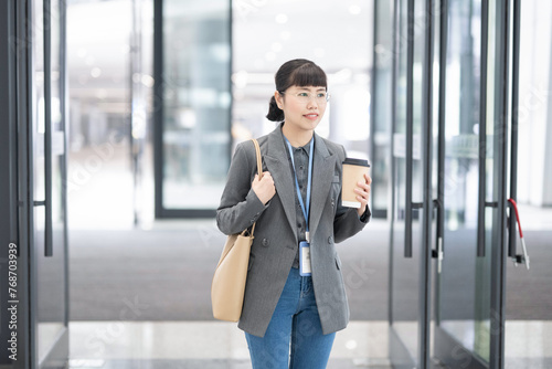 White-collar workers carrying coffee to work in the morning walk into the lobby of the office building