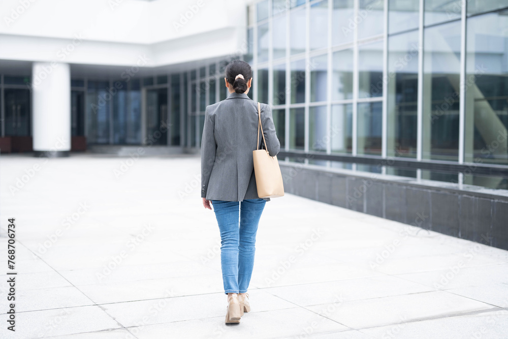 Back view of professional woman entering office building for work