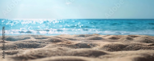 A photo of an empty sandy beach with the ocean in the background, blue sky, blurred bokeh effect, closeup shot.