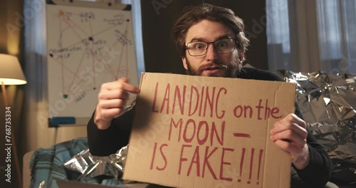 A paranoid, a supporter of pseudoscience holds a sign with a conspiracy slogan.