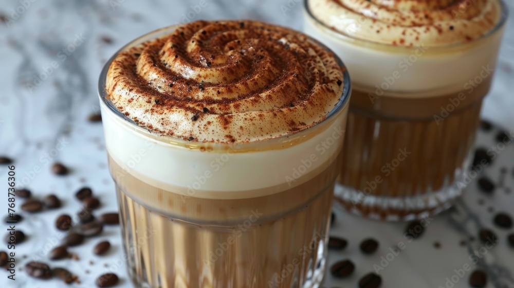 Two glasses of hot cocoa with whipped cream on top & coffee beans scattered around on a marble surface Two glasses of hot cocoa with whipped cream on top & coffee beans scattered around on a marble surface